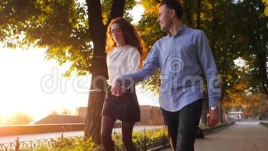 一对男女牵着手在秋城公园奔跑。 时髦的一对或穿商务服装的学生乐意